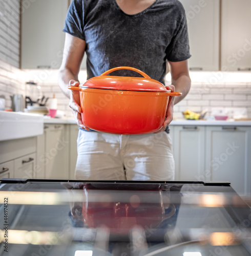 A man holding in his hands orange enamel dutch oven. photo