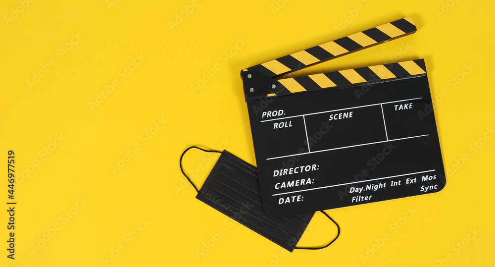 Clapperboard or movie slate and black face mask on yellow background. Yellow and black color.
