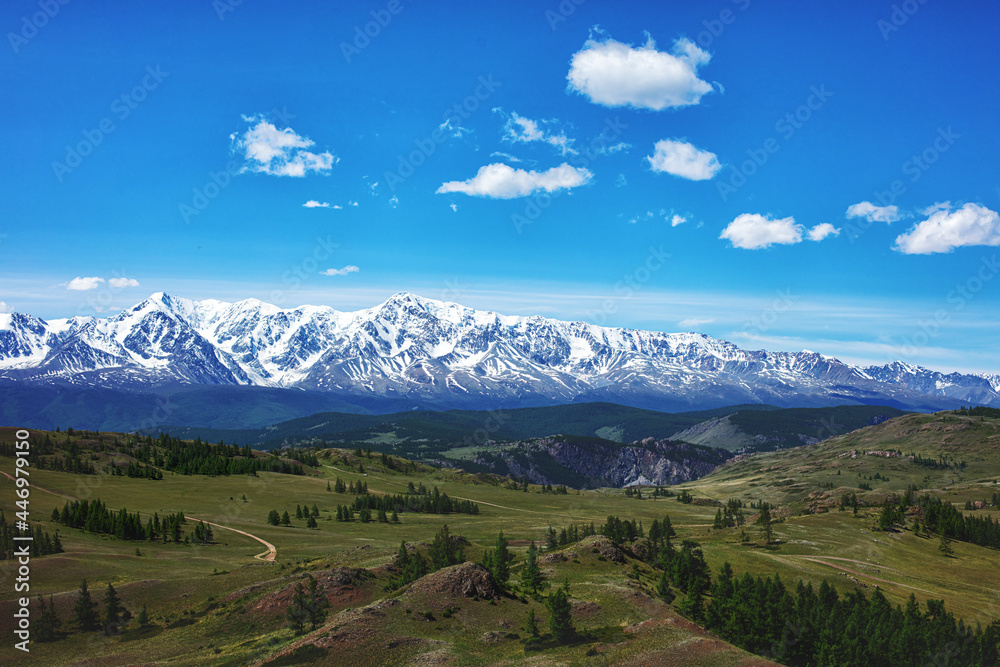 Beautiful landscape with fields, forests and a range of snow-capped mountains