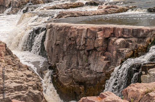 Sioux Falls, SD, USA - June 2, 2008: Closeup of brown-black rock spared from water overflow with splashing white water flows around. photo