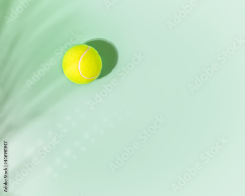 Tennis. Sport, horizontal composition with yellow tennis ball and palm leave shadow on mint background with place for text. Flat lay