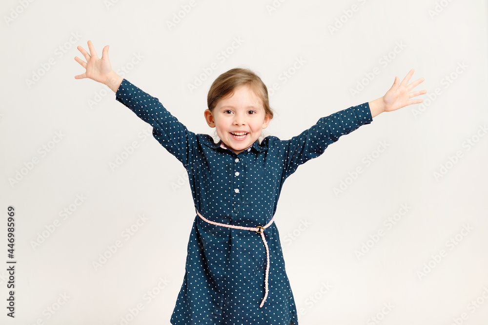 Happy little girl wearing a blue dress raised her hands in different directions. Freedom, joy, school holidays Happy little girl wearing a blue dress raised her hands in different directions. Freedom, joy, school holidays