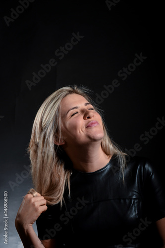 Attractive blonde cute girl grimaces on a dark background in the studio.