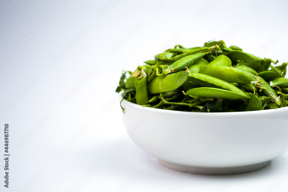 White cup with green peas in pods, on a white background, advertising a healthy lifestyle, daily rate of protein and fiber. White cup with green peas in pods, on a white background, advertising a healthy lifestyle, daily rate of protein and fiber.