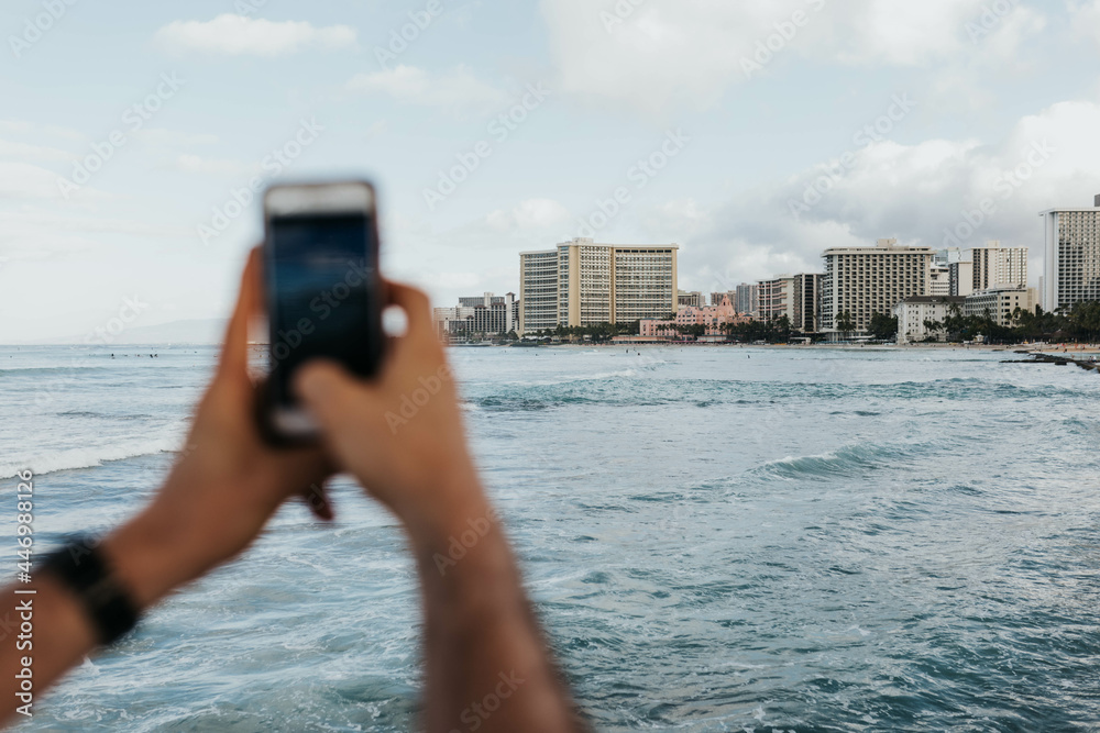 Adult man takes photo of the Waikiki neighborhood and shoreline