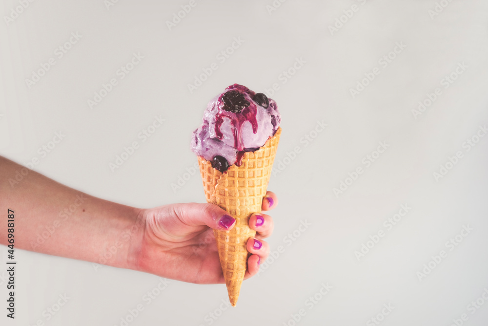 © Cavan Images - Hand holding berry ice cream in a waffle cone