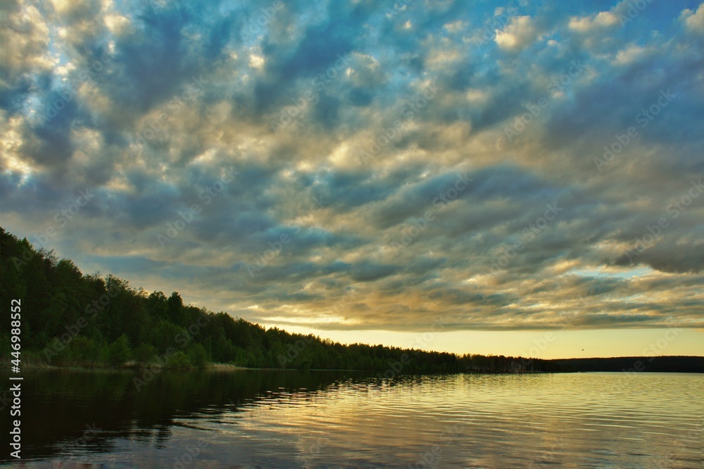 Fototapeta premium Ragged clouds over a forest lake at sunset