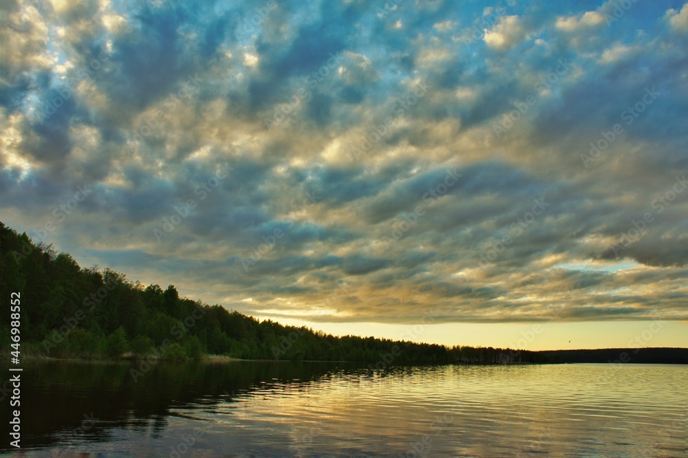 Ragged clouds over a forest lake at sunset
