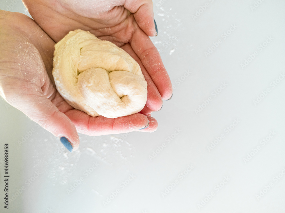 Hands hold dough braided in braid