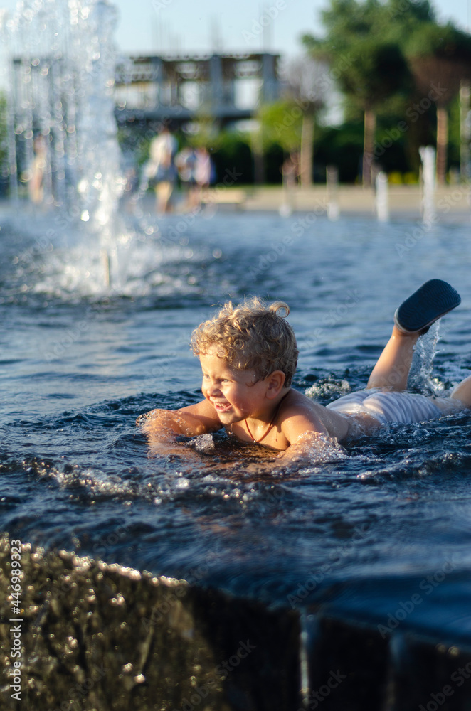 Fototapeta premium boy 2 years old bathes in a fountain, free space