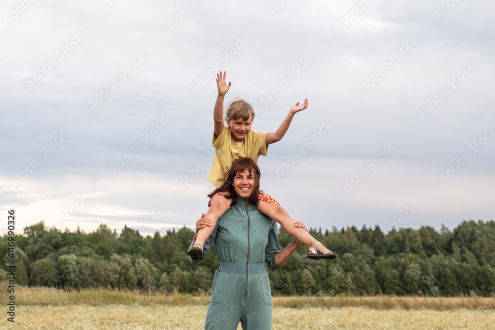 family photo. mom and daughter walk through a chamomile field in the summer. a woman and a child have fun and laugh family photo. mom and daughter walk through a chamomile field in the summer. a woman and a child have fun and laugh