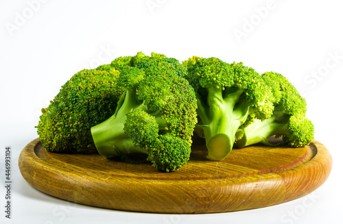 Sliced raw fresh head of broccoli cabbage on a wooden board, white background, healthy vegetarian food, close-up