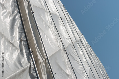 wooden structure covered with white synthetic material tarpaulin - sunlight reflection, summer, late afternoon