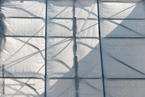 wooden structure covered with white synthetic material tarpaulin - sunlight reflection, summer, late afternoon