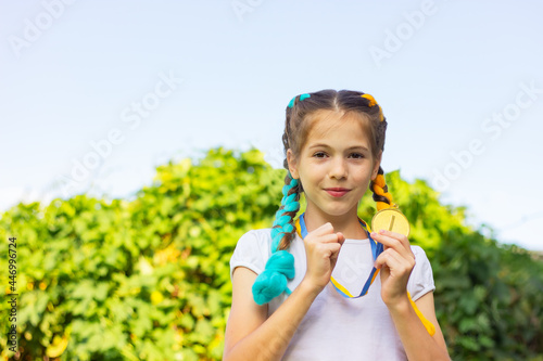 happy girl holding a gold medal in her hands with a copy space