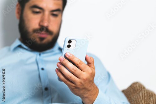 A man with a beard holds a mobile phone and looking in the screen business