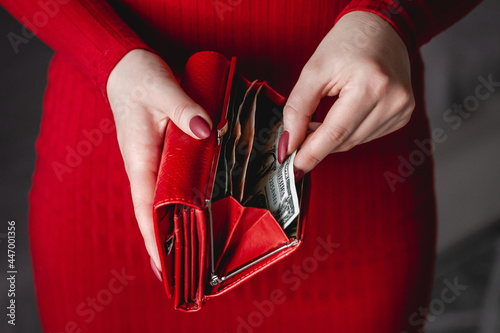 Red wallet in the hands of woman in a red dress with red manicure