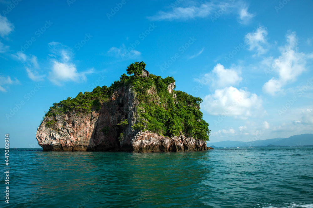 A small tropical island with an old wooden hut on top in the middle of the ocean