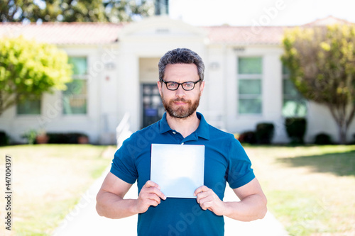 teacher man in glasses showing paper sheet, back to school