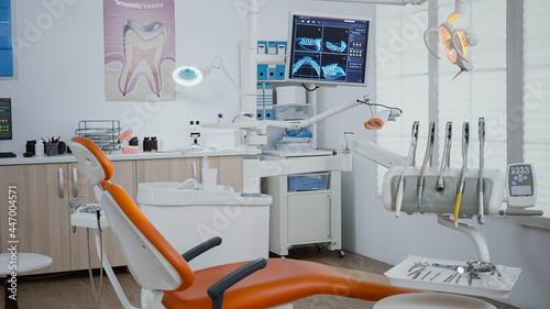 Interior of modern equipped dental orthodontic office with teeth x ray images on monitors, medical dentist stomatology workplace. Zoom in shoot. Empty clinic cabinet for teethcare treatment