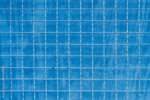 Metal mesh with square cells on blue painted background