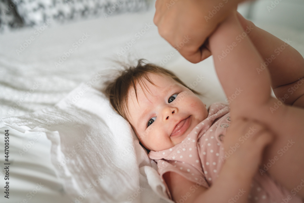 Happy caucasian baby four months old smiling happy while unknown parent is cleaning her and changing her diapers copy space Happy caucasian baby four months old smiling happy while unknown parent is cleaning her and changing her diapers copy space