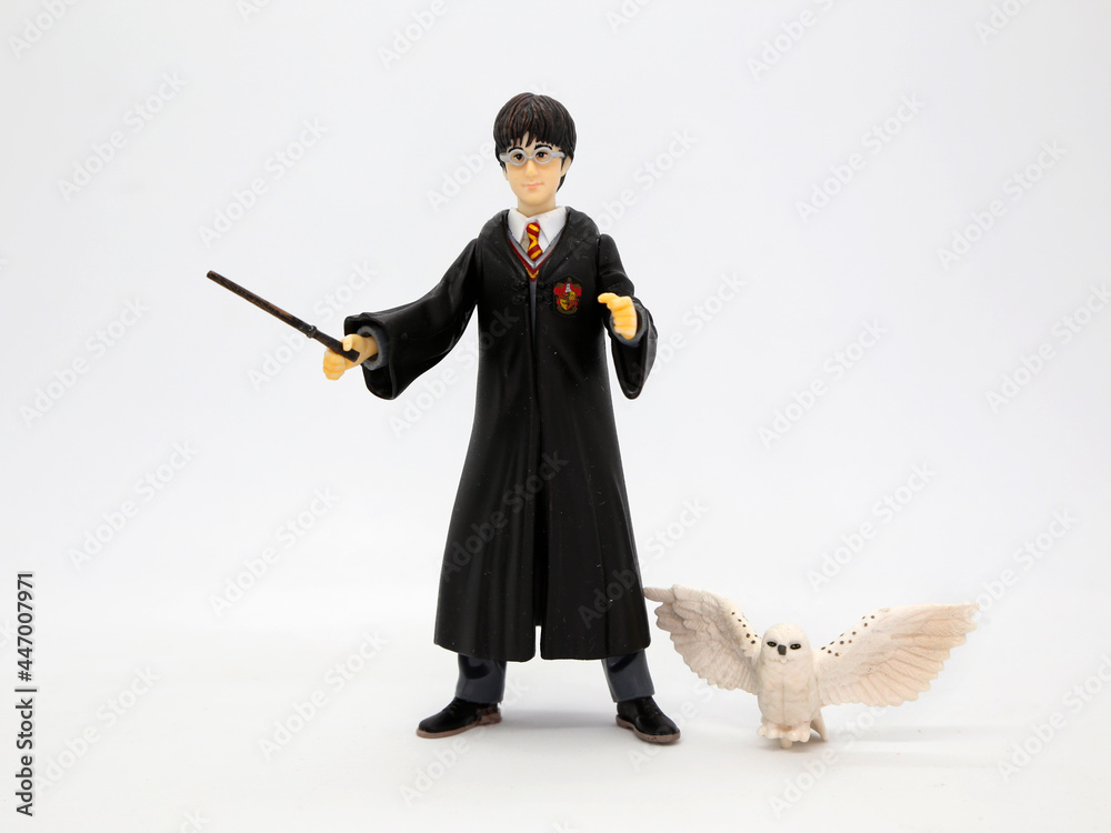 Fototapeta premium Harry Potter with his white owl Hedwig. Harry dressed in his Hogwarts School of Witchcraft and Wizardry uniform and his wand in hand. Collectible toy for children. Character from the J. K. Rowling.
