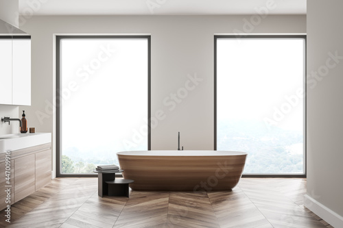 Modern bathroom interior with wood and stone decor elements and big window. Concept of contemporary design and spa relaxation.