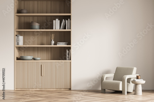 Light beige living room wall with lined bookcase and armchair