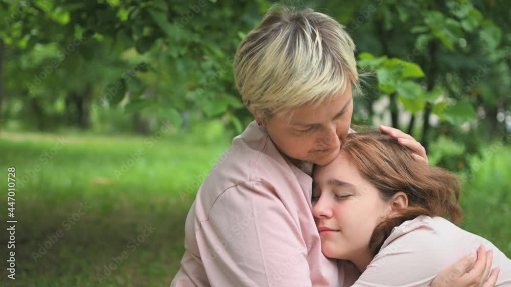 A mother calms her crying daughter sitting on a blanket in the park. Transitional age. First love. A mother calms her crying daughter sitting on a blanket in the park. Transitional age. First love.