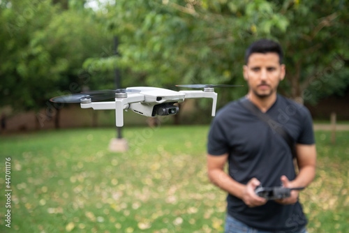Hombre joven piloteando un mini dron en un parque
