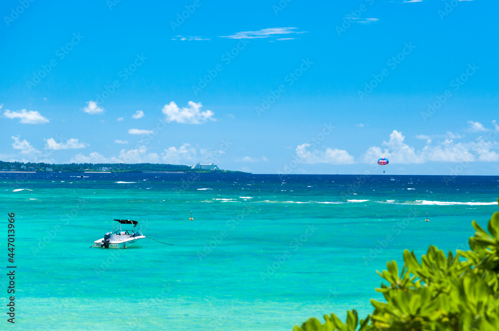 沖縄ブセナのエメラルドグリーンの海とパラセーリング