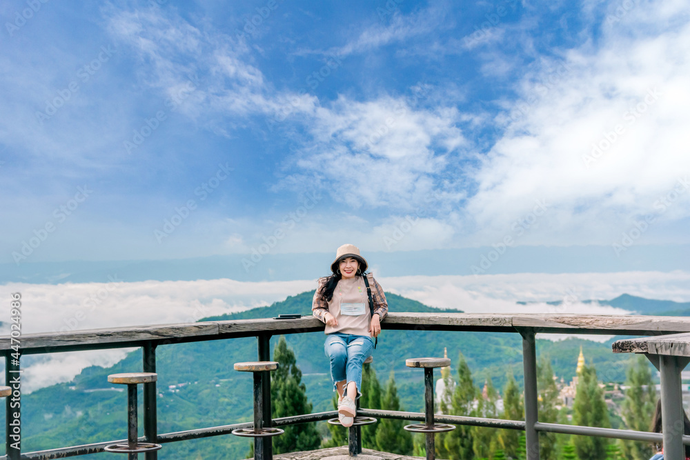 woman sitting on wooden balcony looking at mountain and fog view travel