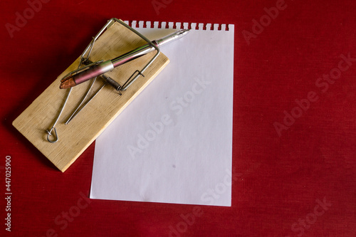 A fountain pen on a mousetrap on a sheet of writing paper for notes.