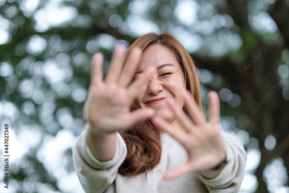 Portrait image of a beautiful young asian woman raising hands and playing with camera in park Portrait image of a beautiful young asian woman raising hands and playing with camera in park