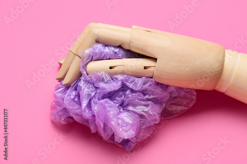 Wooden hand with garbage bag on color background. Ecology concept