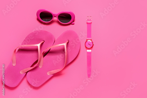 Stylish sunglasses, wrist watch and flip-flops on color background