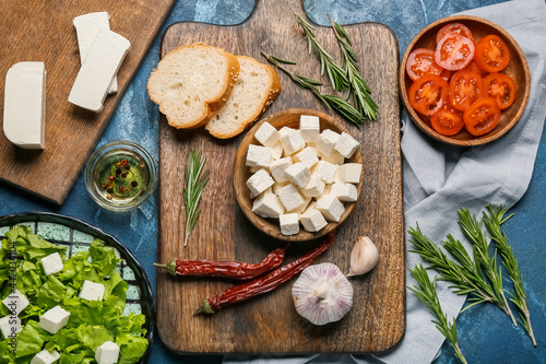 Composition with delicious pieces of feta cheese and ingredients on color background