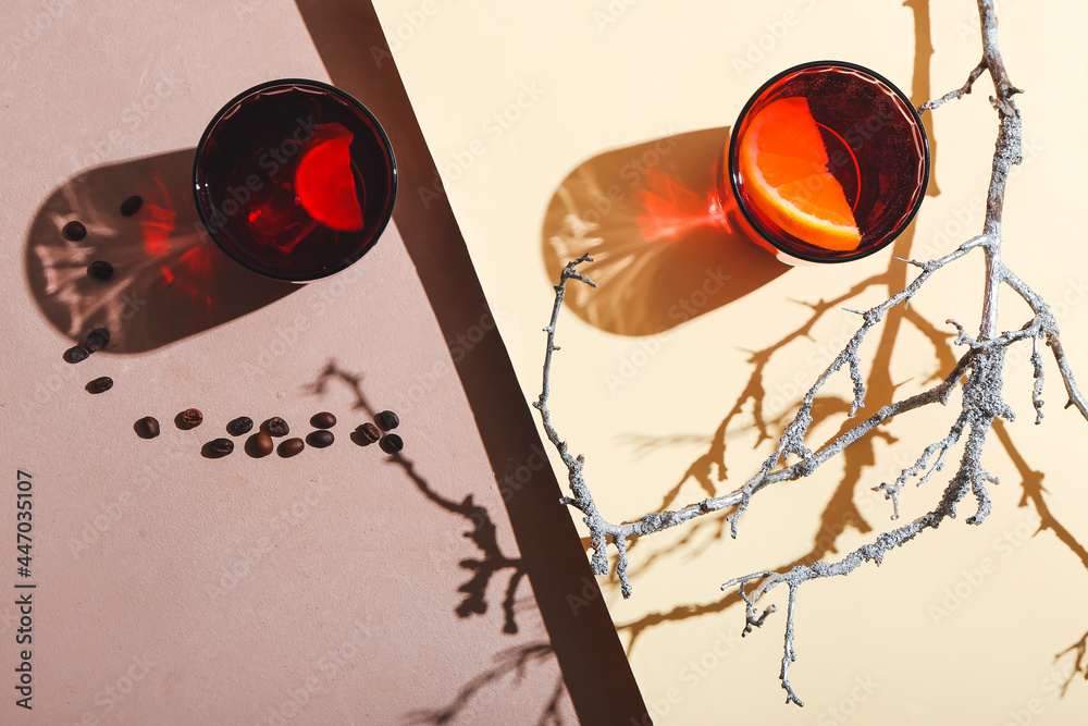 Glasses of tasty cocktails with coffee beans and tree branch on color background