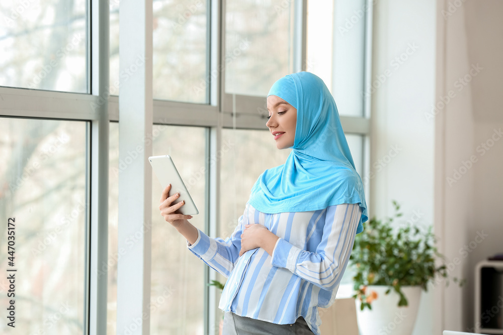 Pregnant Muslim woman using tablet computer in office Pregnant Muslim woman using tablet computer in office