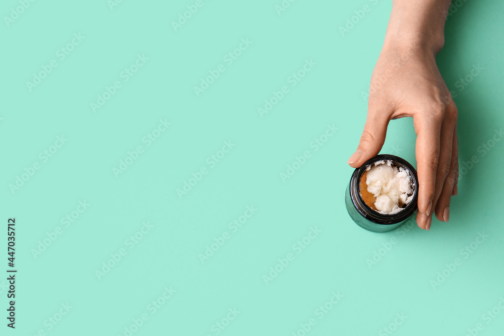 Female hand with jar of shea butter on color background Female hand with jar of shea butter on color background