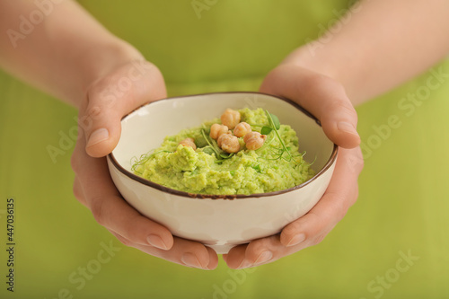 Woman with tasty green pea hummus in bowl, closeup
