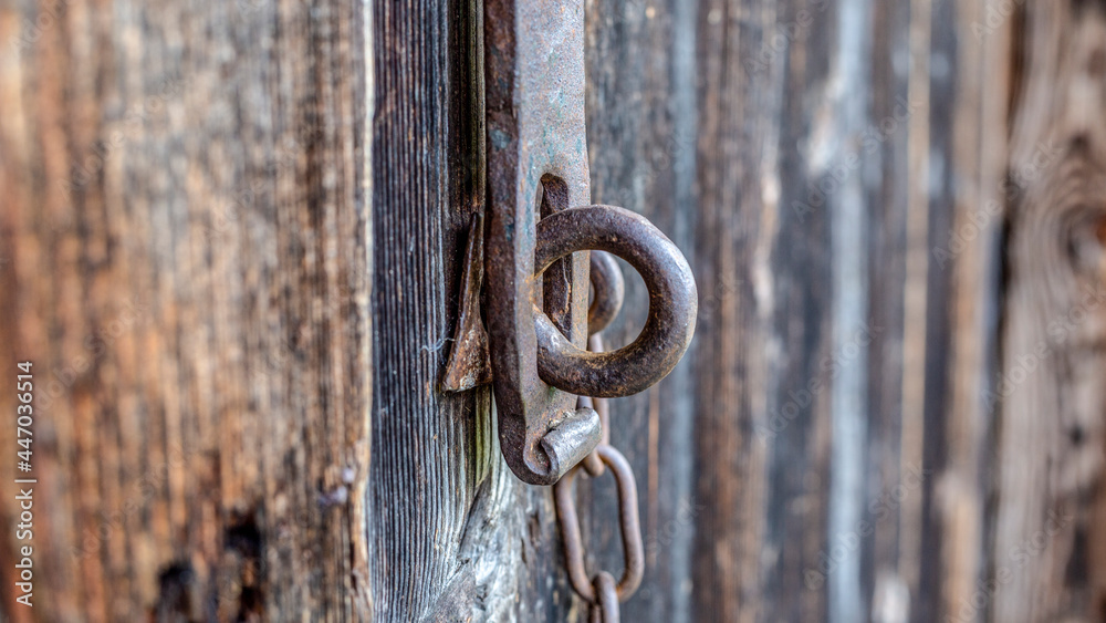 Old lock in the form of a rusty ferruginous ring. Closes from top to bottom by throwing a metal clip with curved edge. Hanging on a chain. A beautiful antique item. Close-up, macro, bokeh. Green brown Old lock in the form of a rusty ferruginous ring. Closes from top to bottom by throwing a metal clip with curved edge. Hanging on a chain. A beautiful antique item. Close-up, macro, bokeh. Green brown