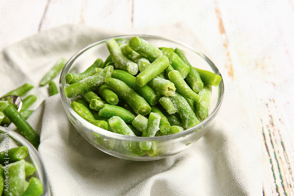 Bowl with frozen green beans on light wooden background Bowl with frozen green beans on light wooden background