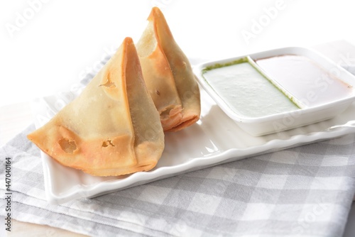 deep fried indian curry potato vegetable samosa snack with green mint yogurt sauce in white background dim sum snack Halal menu photo