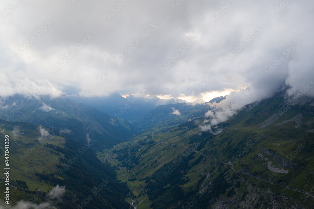 Tolle Drohneaufnahmen in den schweizer Alpen. Wundervolle grüne Bäume und ein mächtiger Wasserfall in mitten des Waldes. Vogelperspektive.