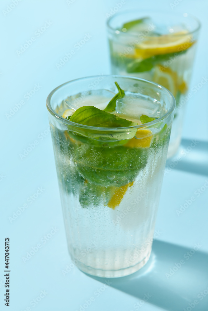 Glasses of tasty lemonade with basil on color background Glasses of tasty lemonade with basil on color background