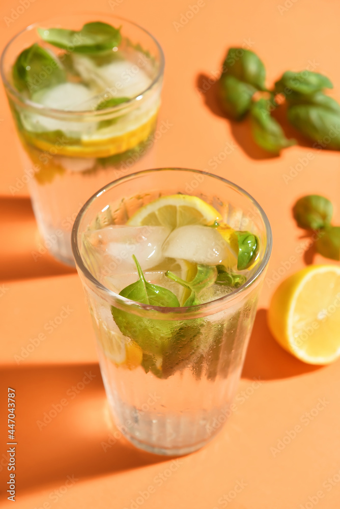 Glasses of tasty lemonade with basil on color background
