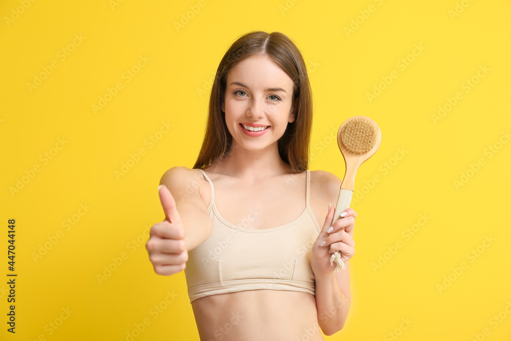 Beautiful young woman with massage brush showing thumb-up on color background Beautiful young woman with massage brush showing thumb-up on color background