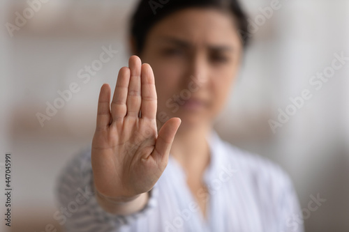 Close up focus on Indian woman showing stop gesture at camera, blurred background, strong young female protesting against domestic violence and abuse, bullying, saying no to gender discrimination photo